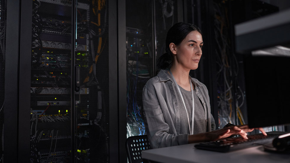 A woman working on a computer in a server room.